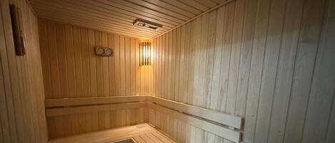 A wooden sauna with benches and a wall-mounted clock.