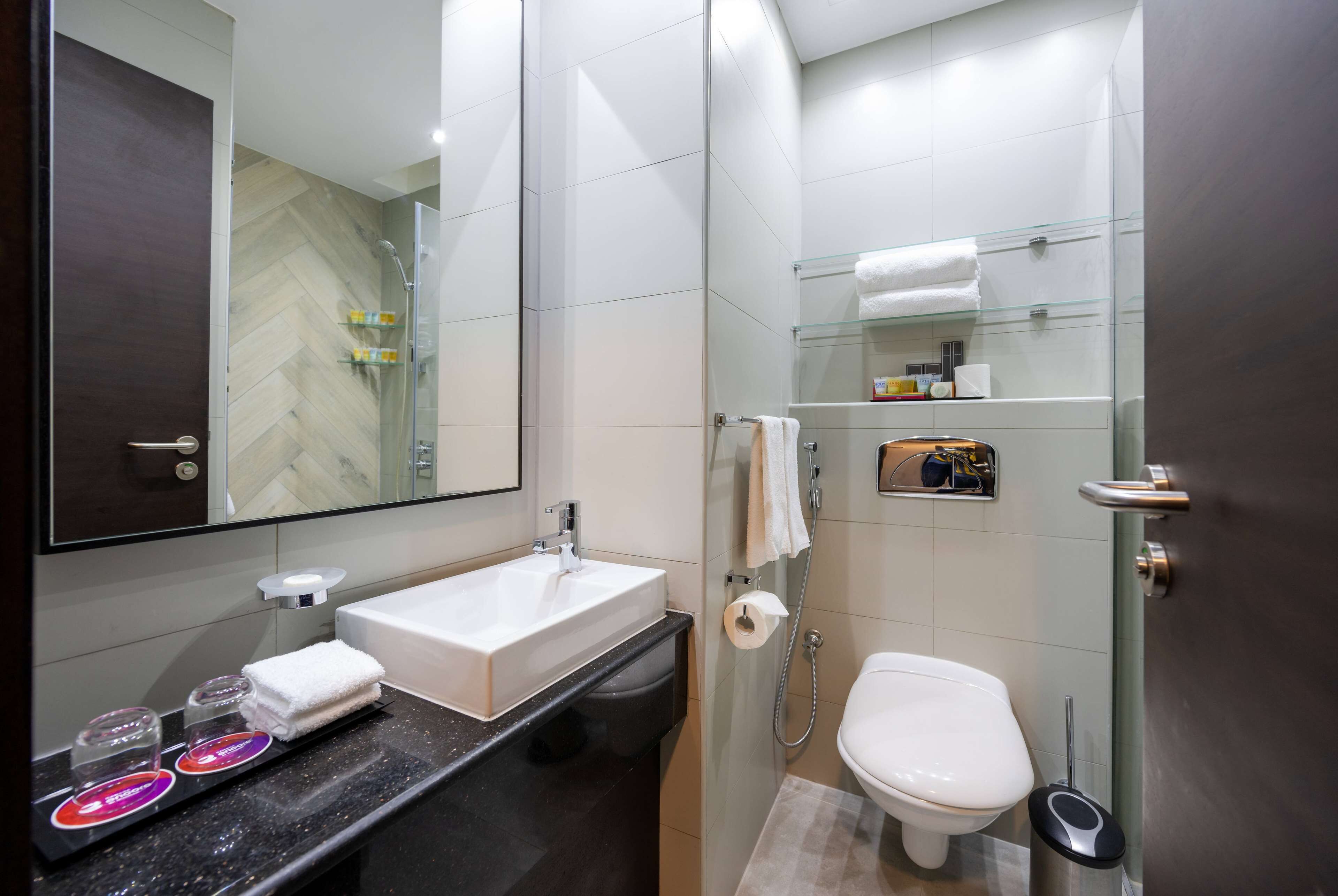 A modern bathroom with a glass shower enclosure, a white sink, and a toilet.