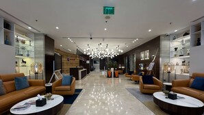 A modern lobby with leather sofas, marble coffee tables, and glass display shelves. - Ramada Encore by Wyndham Doha (Doha)