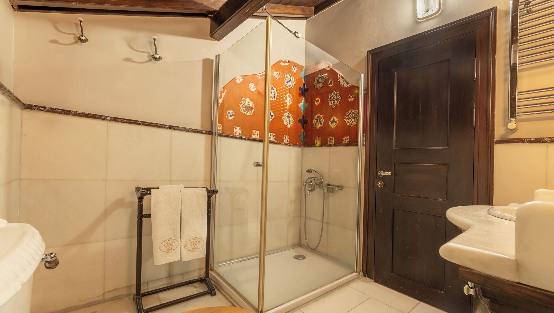 Un baño con cabina de ducha de vidrio, una puerta de madera oscura y un lavamanos blanco.