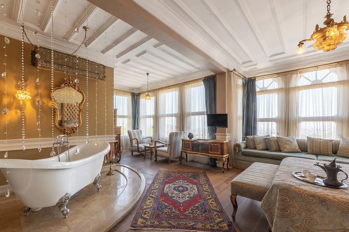 A luxurious room with a grand bathtub, a sofa set, and a chandelier.