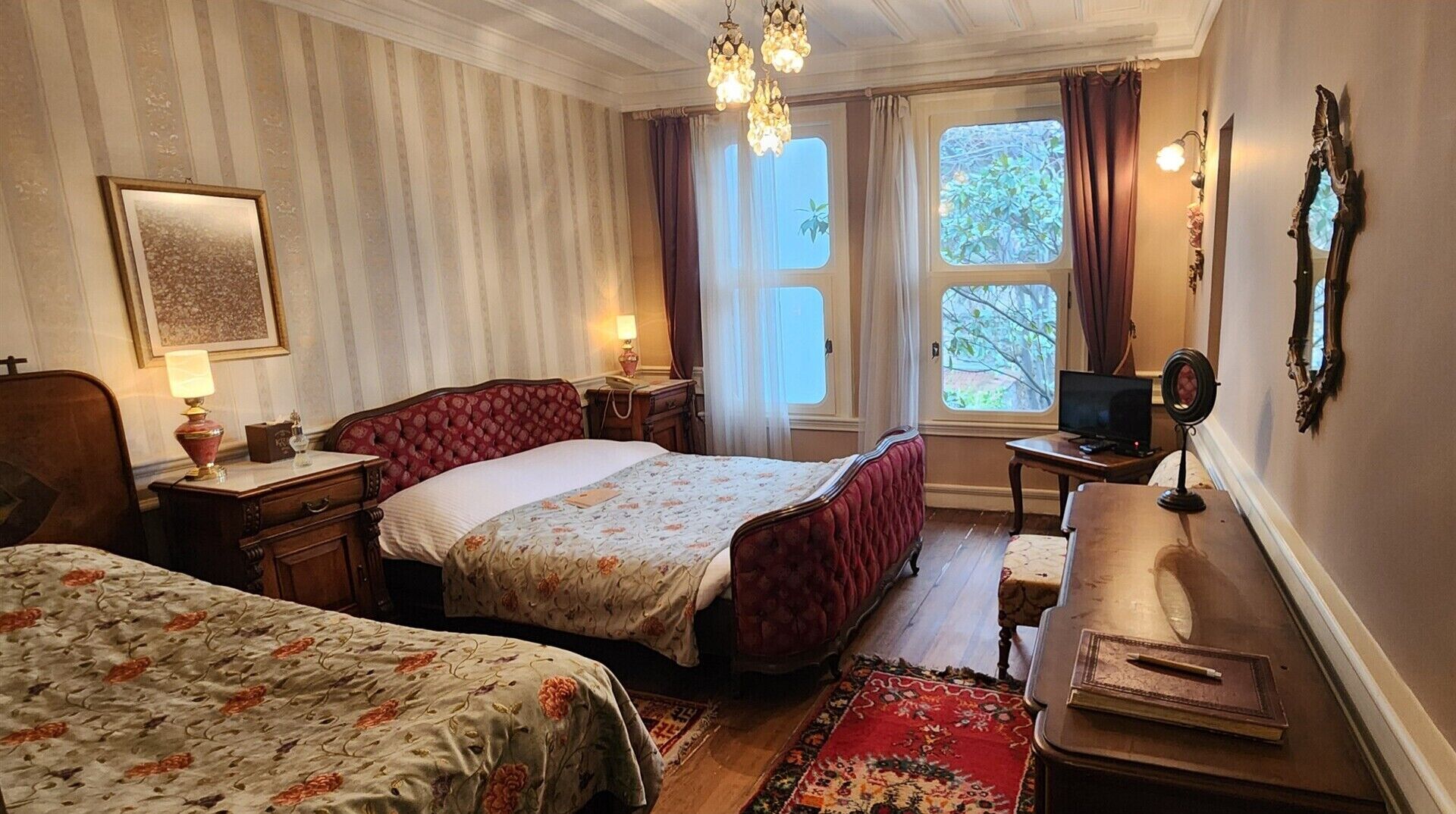 Un dormitorio con dos camas, televisión, escritorio y ventana con cortinas.