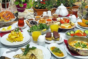 A table set with a variety of breakfast items including bread, fruit, cheese, and beverages. - Kitapevi Special Class Hotel (Bursa)