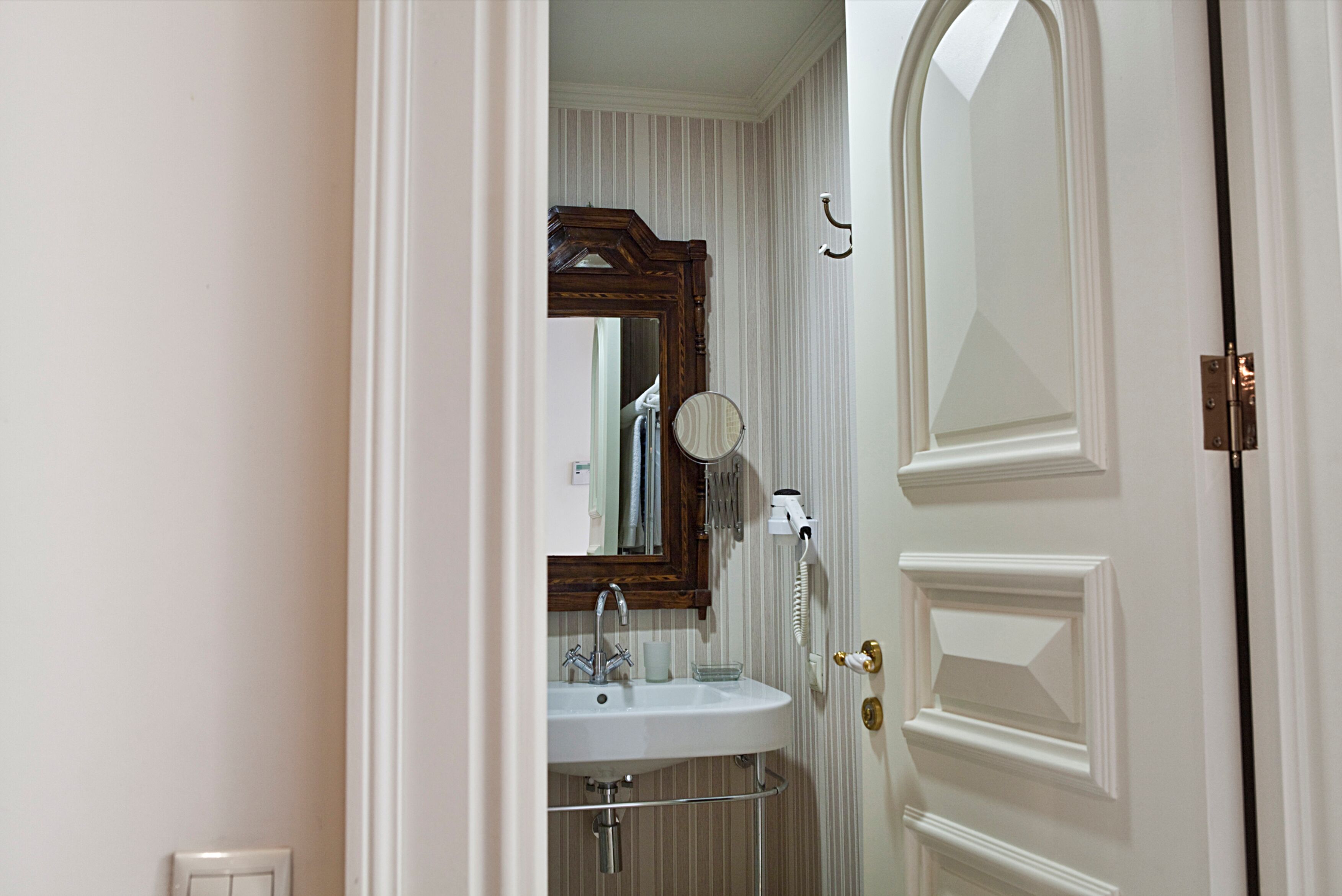 A bathroom with a white sink, mirror, and towel rack.