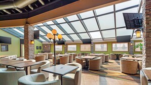 A spacious indoor area with multiple tables and chairs, a glass ceiling, and stone pillars. - Best Western Plus Mirage Hotel & Resort (High Level)