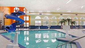 An indoor swimming pool with a blue slide, a basketball hoop, and palm trees. - Best Western Plus Mirage Hotel & Resort (High Level)