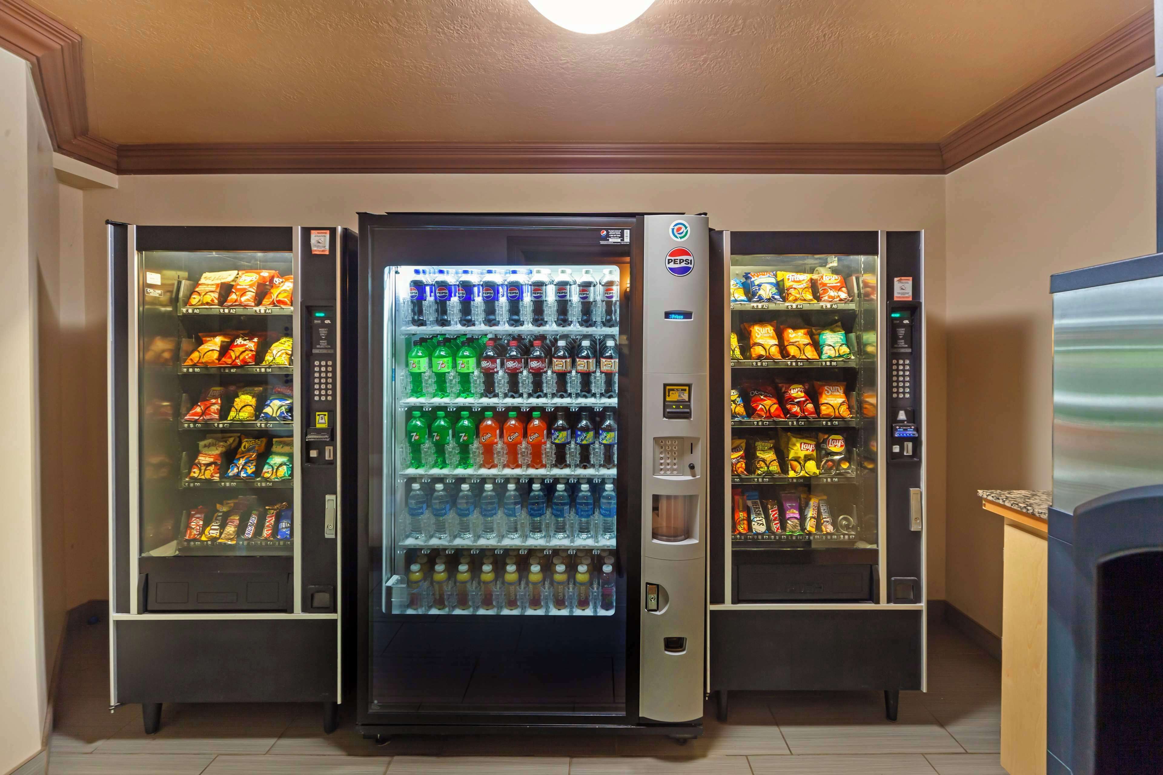 Et automat område med flere drikke- og snacks muligheder, inklusive Pepsi, vand og forskellige snacks.