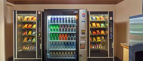 Et automat område med flere drikke- og snacks muligheder, inklusive Pepsi, vand og forskellige snacks.
