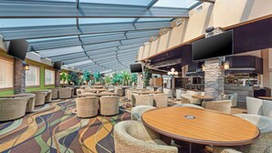 A spacious indoor area with multiple seating arrangements, a bar area, and a large screen. - Best Western Plus Mirage Hotel & Resort (High Level)