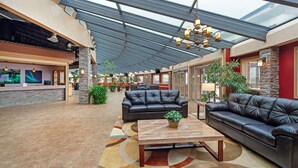 A spacious lobby with a high ceiling, leather sofas, a wooden coffee table, and a reception desk. - Best Western Plus Mirage Hotel & Resort (High Level)