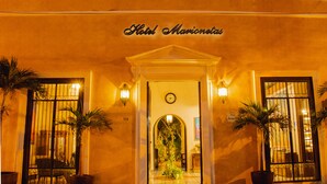 L’hôtel Marienetas se distingue par son entrée classique, une horloge au-dessus de la porte et des plantes en pot de chaque côté.