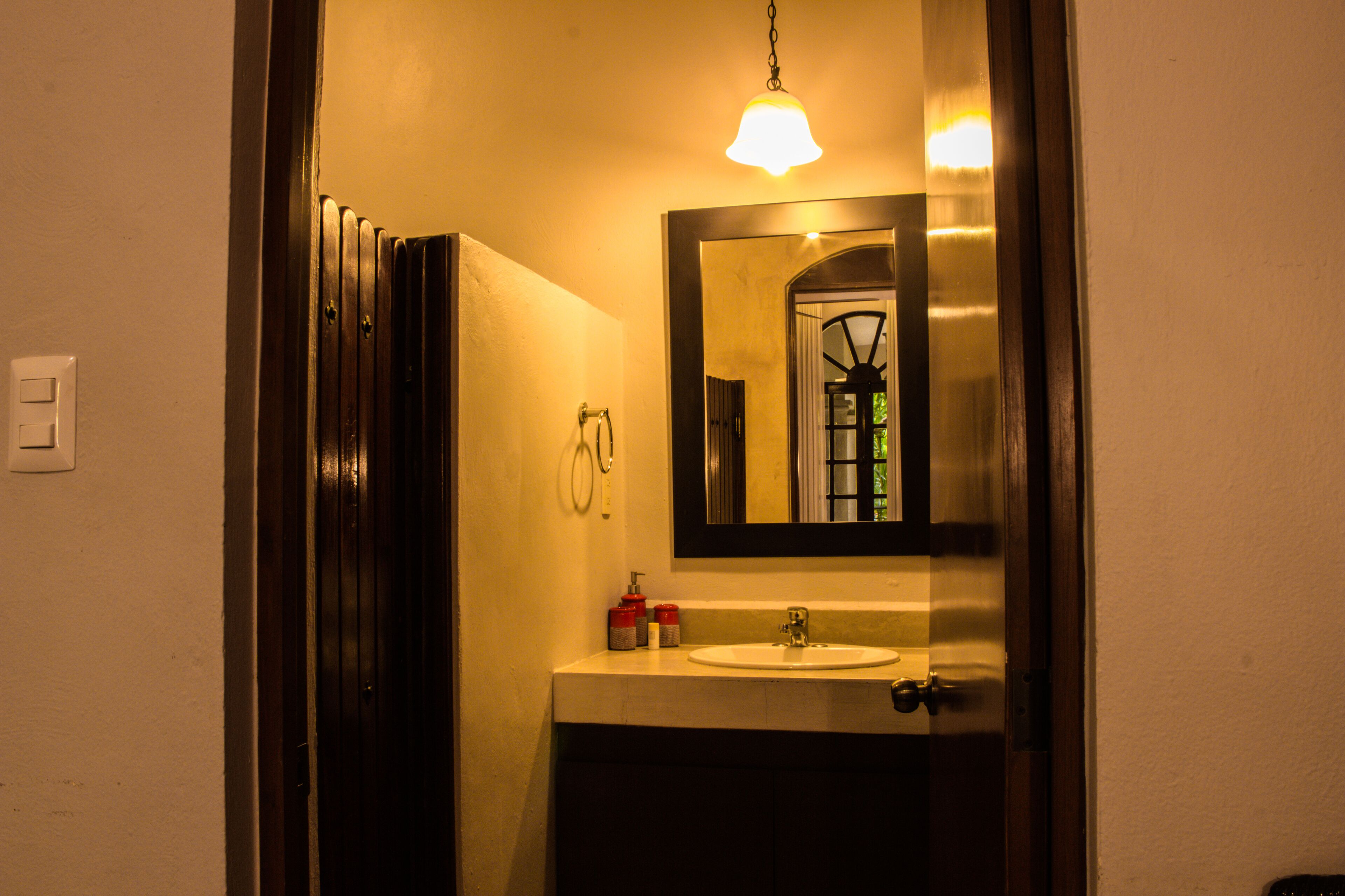 A bathroom with a sink, mirror, and hanging light fixture.