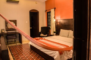 Un dormitorio con cama, escritorio, silla y hamaca.