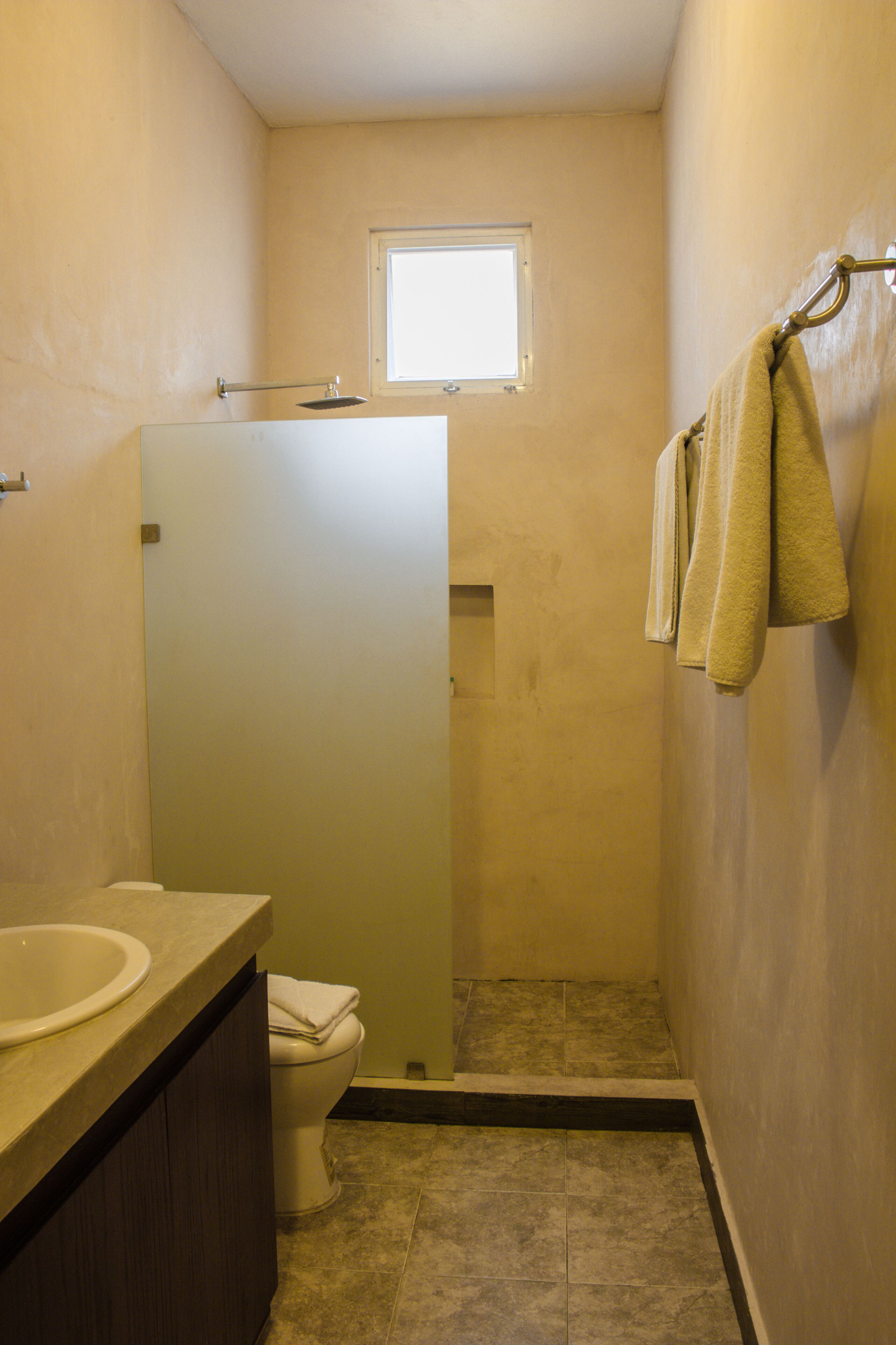 A bathroom with a toilet, sink, and a shower area.