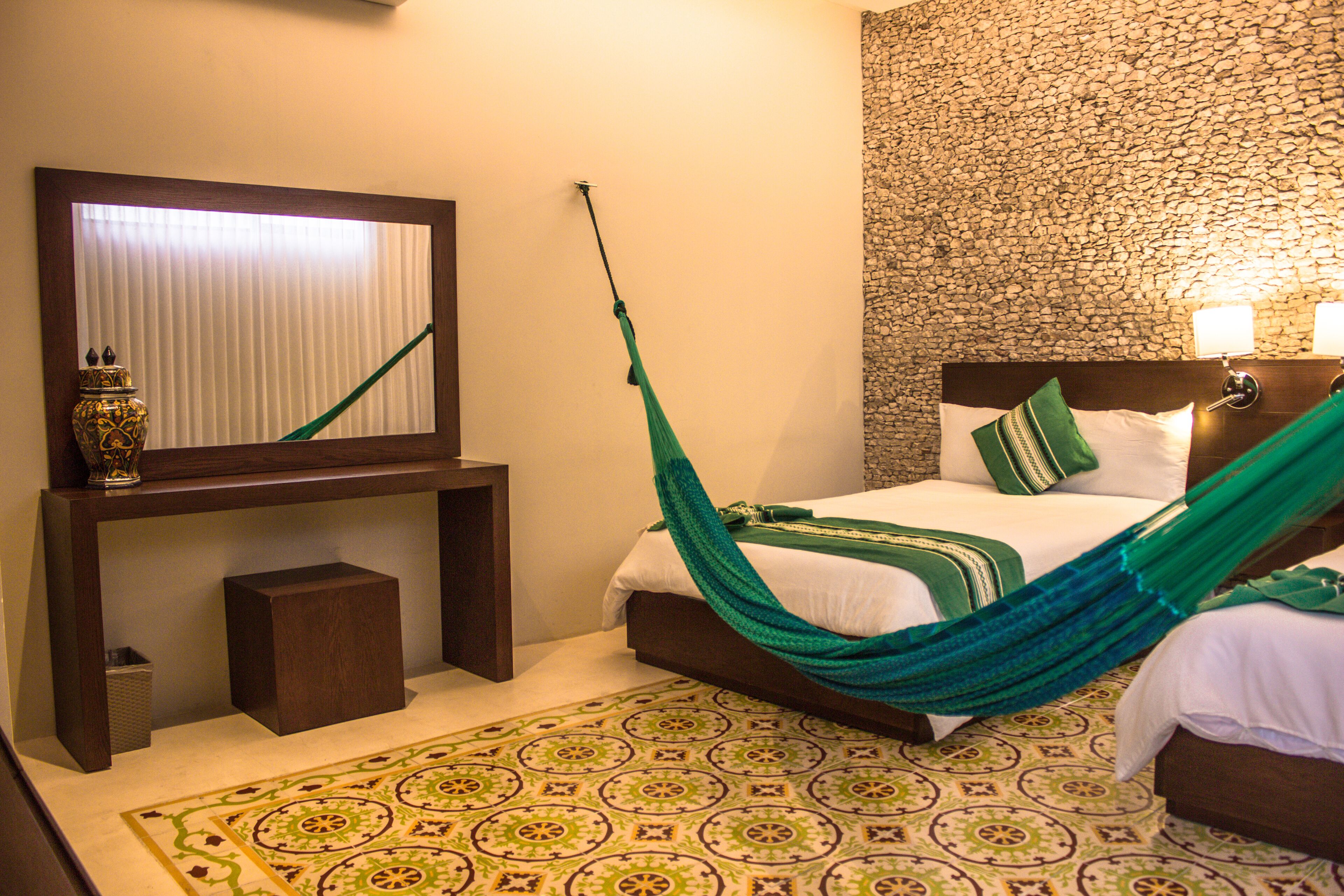A room with a bed, a nightstand, a mirror, and a patterned floor.