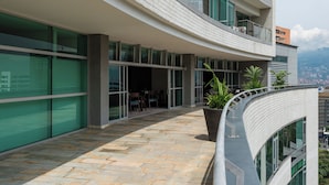 A modern building with a curved balcony, large windows, and a stone-paved walkway.