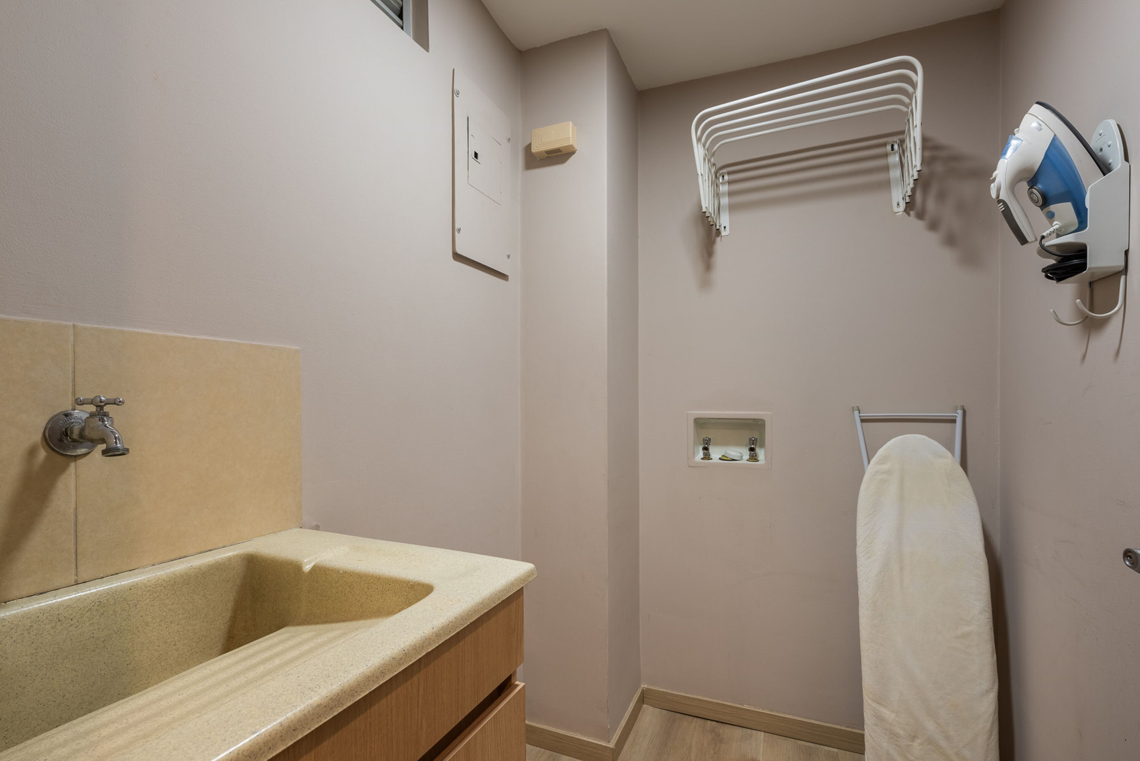 Casa de banho com lavatório, porta-toalhas e secador de cabelo fixado na parede.