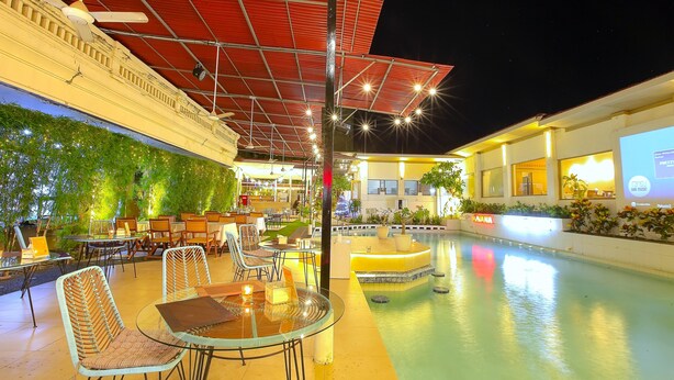 An outdoor pool area with tables and chairs, a covered seating area, and a bar. - Lavender Villa and Spa (Kuta)