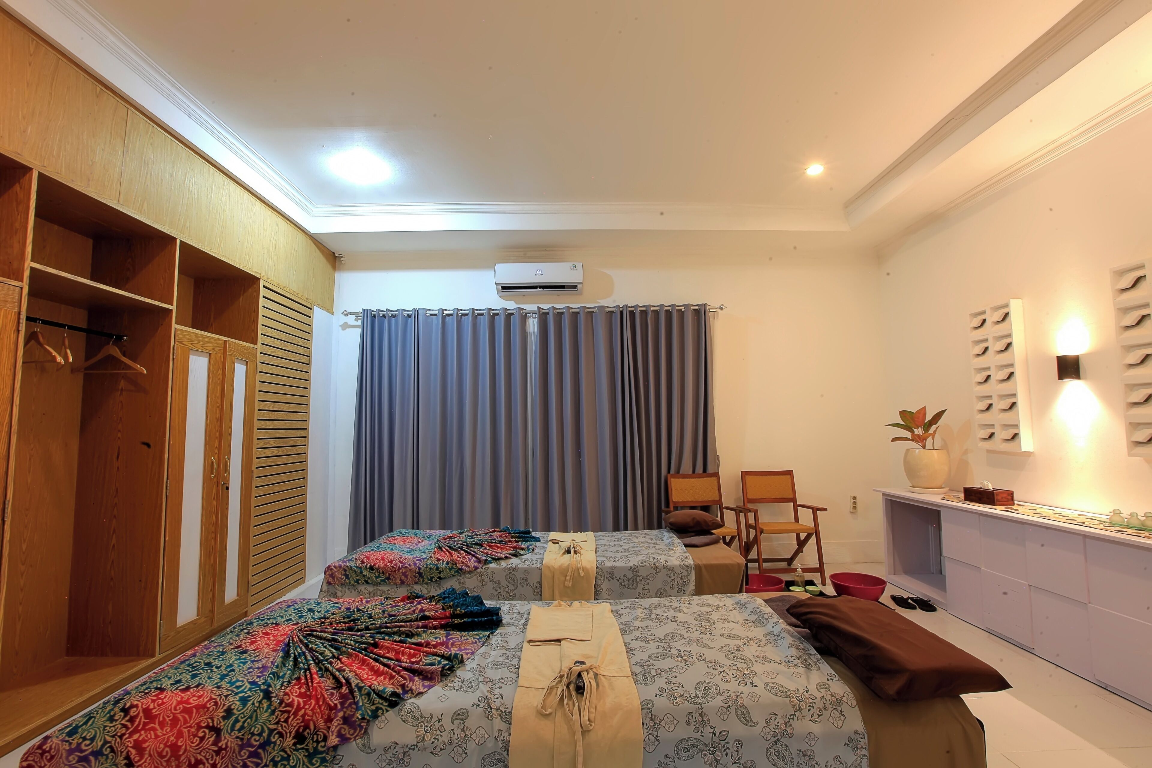 Quarto com duas camas, guarda-roupa, escrivaninha e espelho.