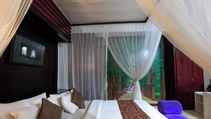 A bed with white and brown pillows, a patterned bed runner, and sheer curtains. - Lavender Villa and Spa (Kuta)