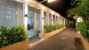 A hotel corridor with a well-lit entrance, potted plants, and a clear pathway. - Lavender Villa and Spa (Kuta)