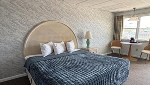 Una habitación de hotel con una cama grande, un escritorio, una lámpara y una ventana con cortinas.