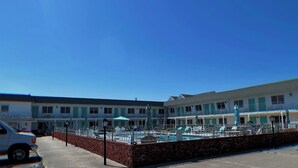 Un hotel con zona de piscina, asientos al aire libre y un muro de ladrillo.