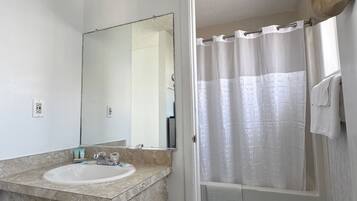 A bathroom with a sink, mirror, shower curtain, and towel rack.