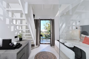 Une chambre d’hôtel moderne avec un escalier, un balcon doté de mobilier d’extérieur et un lit avec des serviettes.