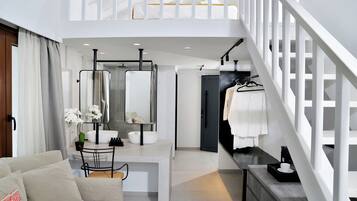 A modern hotel room with a dining area, a staircase, and a view of the city.