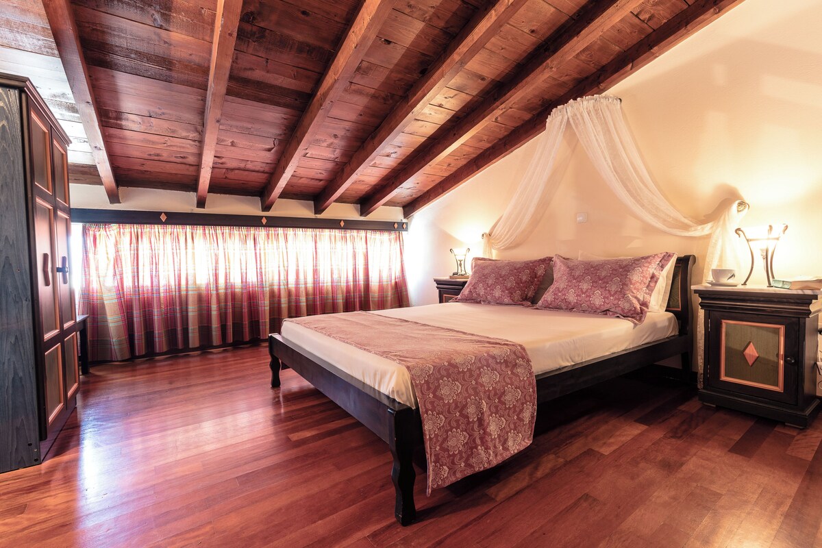 A bedroom with a wooden ceiling, a bed with a canopy, a nightstand, and a wardrobe.