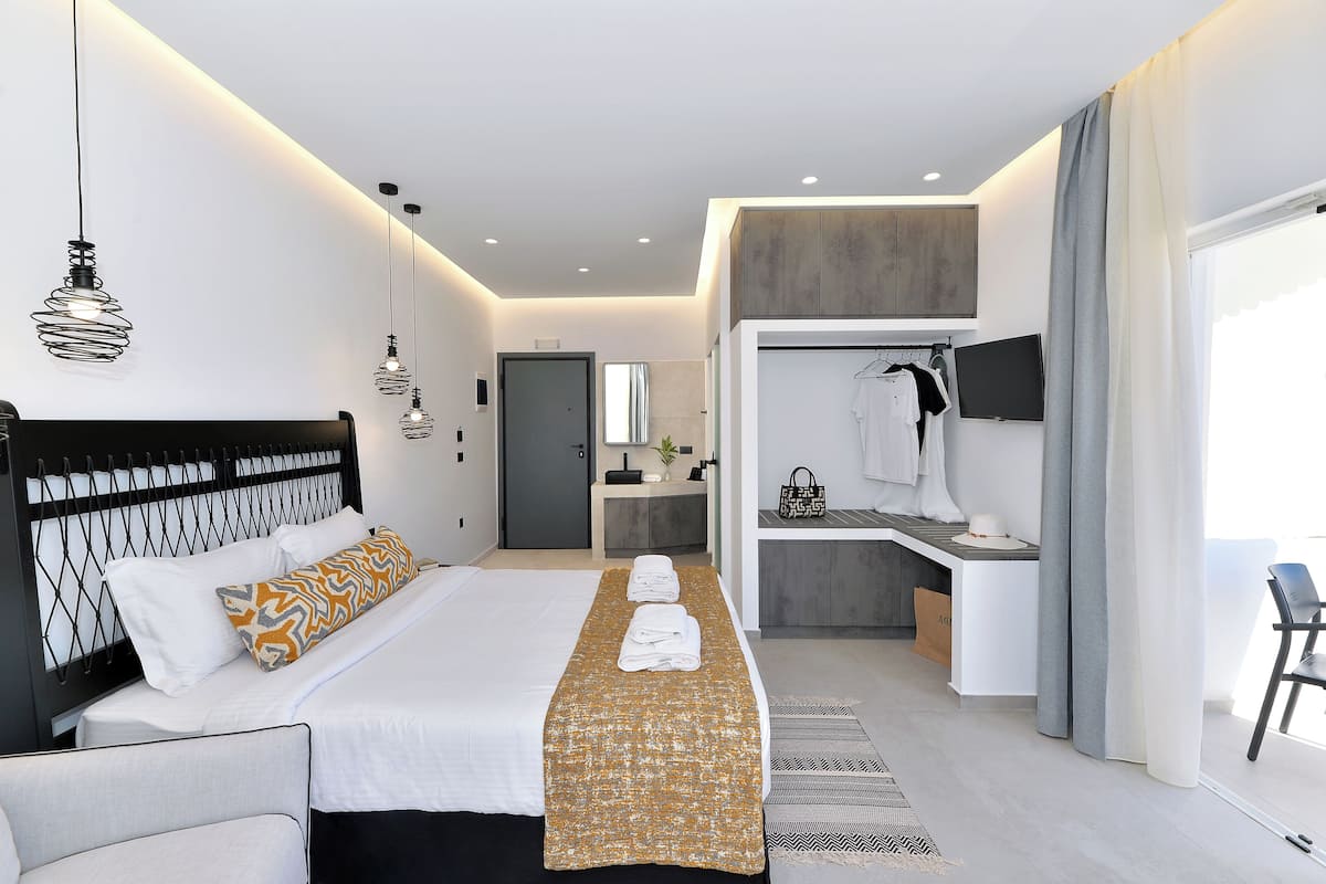 A modern hotel room with a bed, bedside tables, a vanity, a TV, and a bathroom.