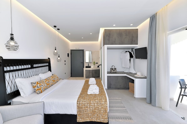 Une chambre d’hôtel moderne équipée d’un lit, de tables de chevet, d’une coiffeuse, d’un téléviseur et d’une salle de bain.