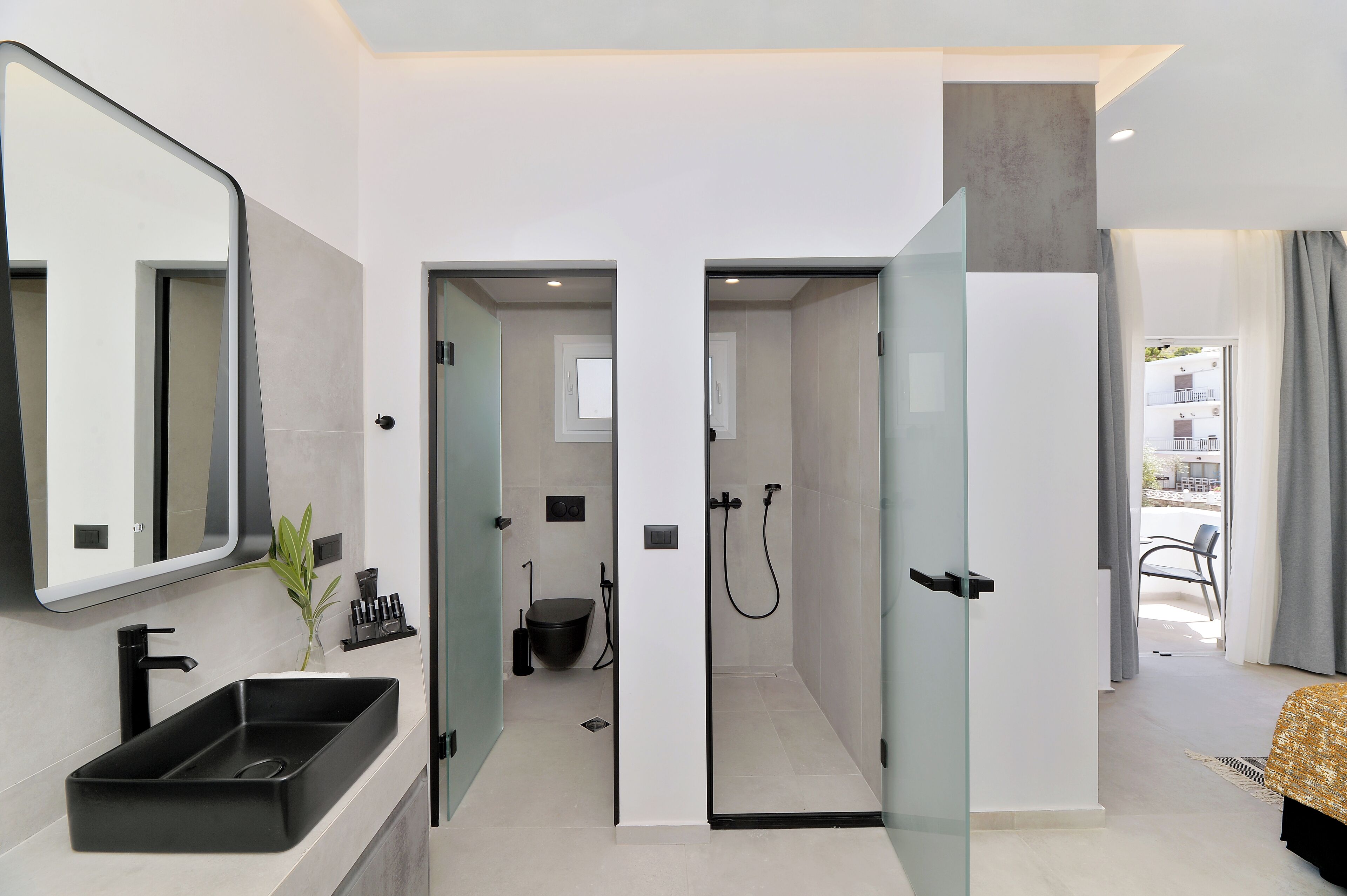 A modern bathroom with a black sink, a mirror, and a shower area.