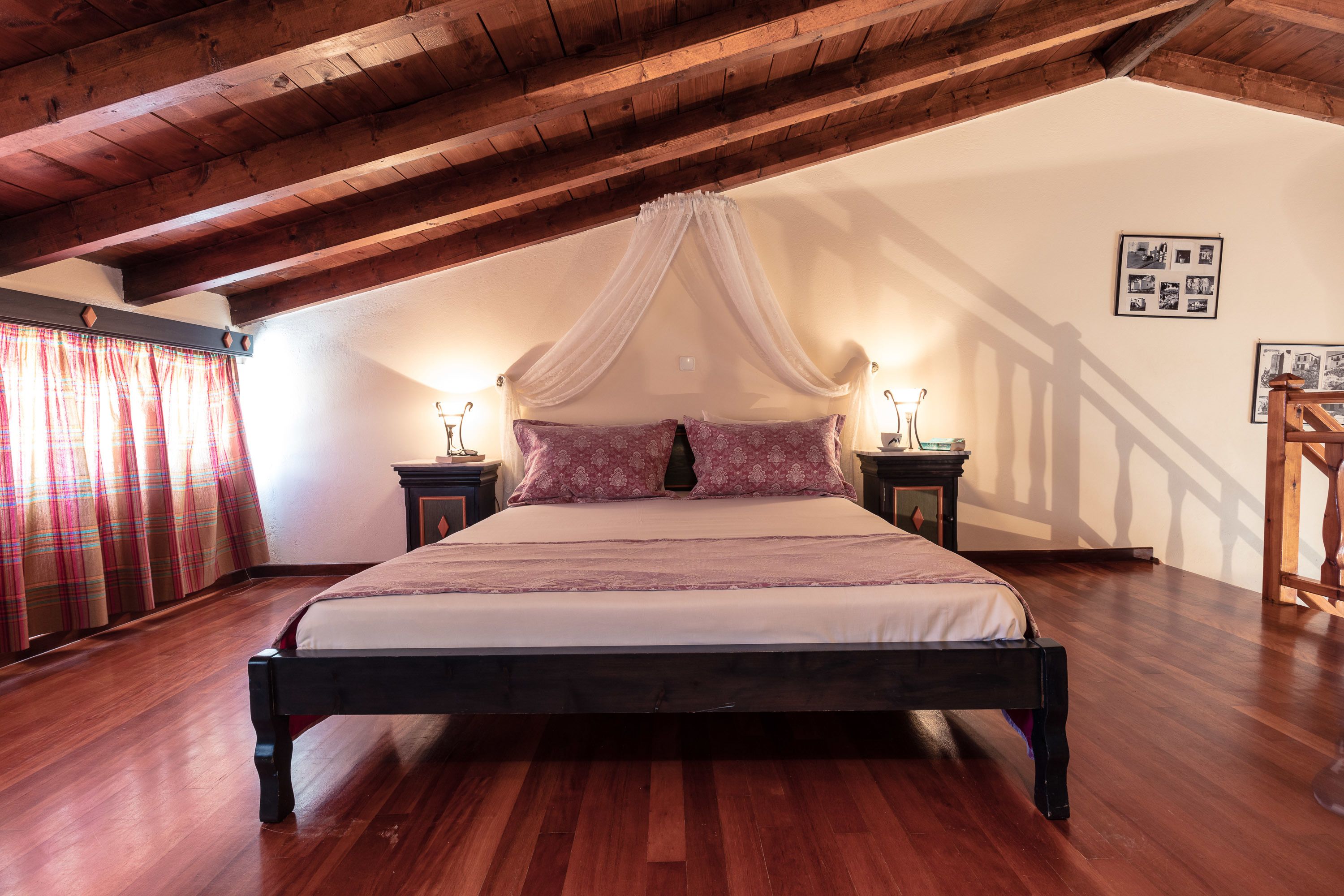 Ein Schlafzimmer mit Holzbalkendecke, einem Himmelbett und zwei Nachttischen mit Lampen.