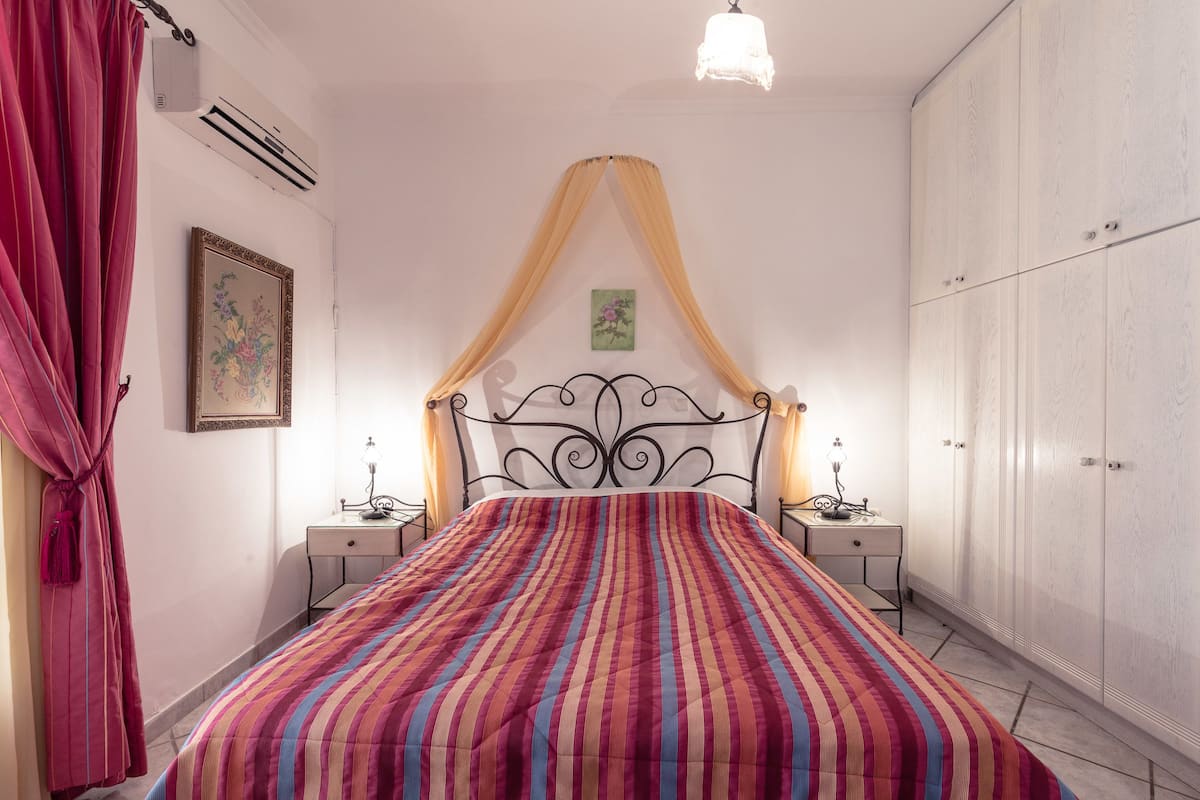 A bedroom with a bed, two bedside tables, a wardrobe, and a hanging light fixture.