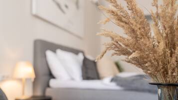 A living room with a sofa, a lamp, and a vase with dried plants.