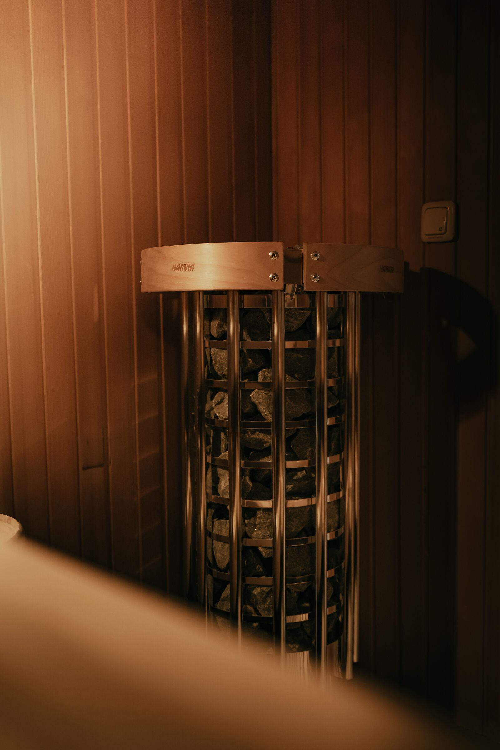 A sauna with a wooden interior and a metal door with the brand name "HARMONIA" visible.