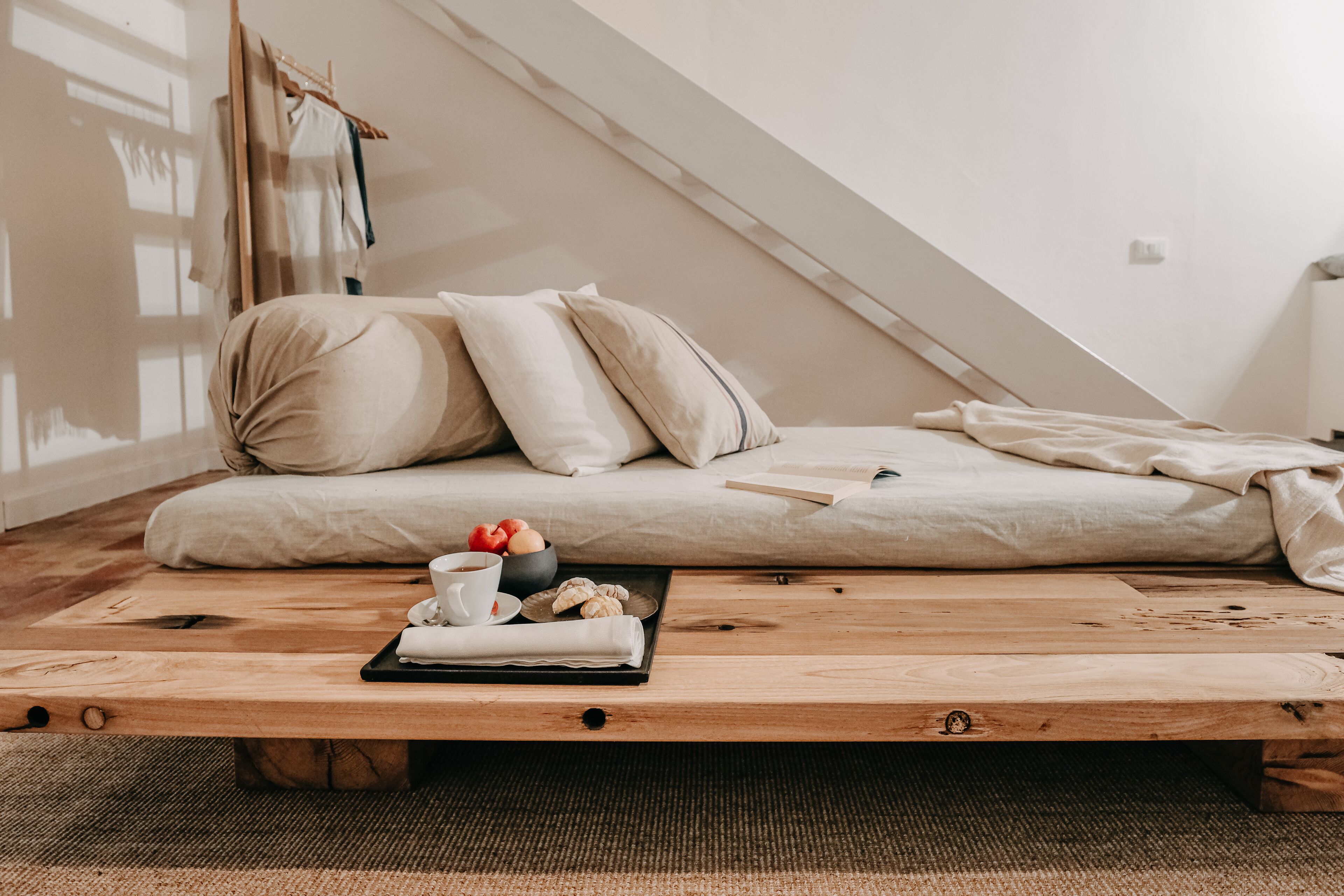 Une chambre de style « loft », avec un lit, une table basse en bois sur laquelle sont disposés des éléments pour le petit-déjeuner, et une vue sur le ciel par une fenêtre.