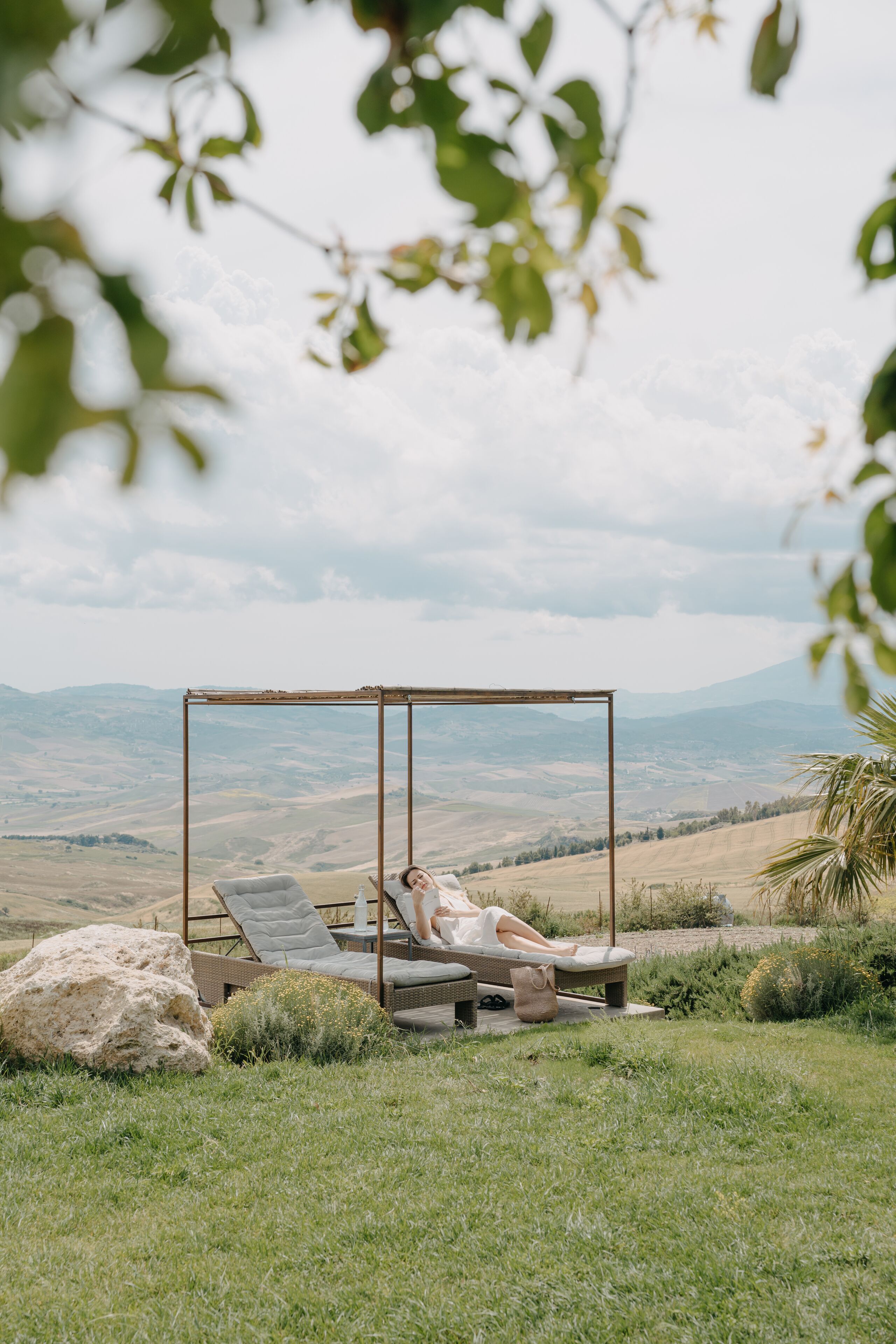 A swing chair in a grassy area with a view of distant hills.