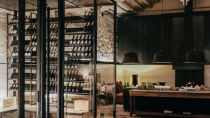 Uma adega com portas de vidro, prateleiras cheias de garrafas de vinho e um chão de tijolos rústicos.
