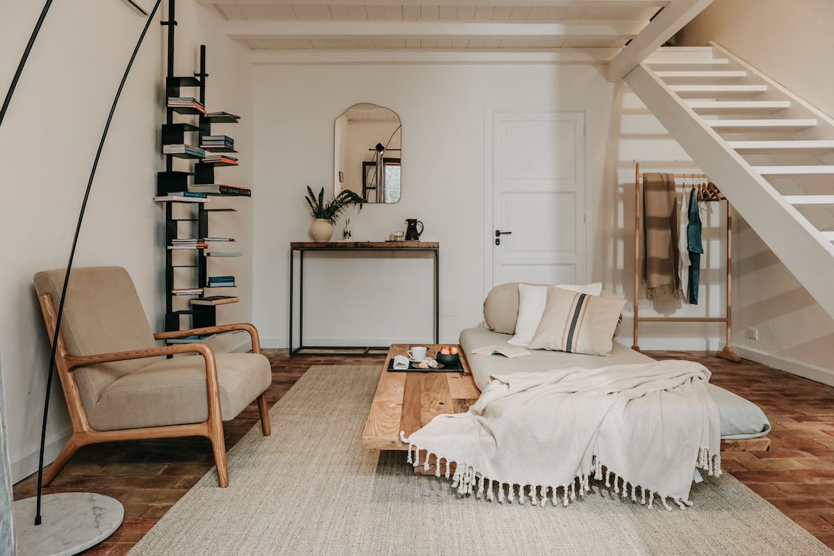 A cozy living room with a sofa, a coffee table, a bookshelf, and a staircase.