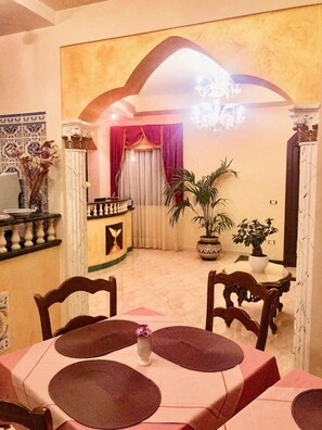 A dining area with a table set for four, chairs, a vase with a flower, and a potted plant. - Araba Fenice Hotel (San Vito Lo Capo)