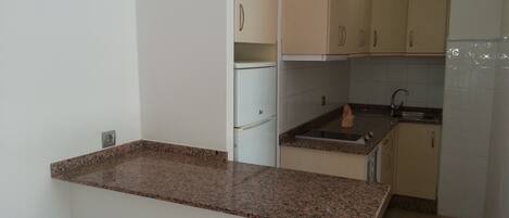 Eine Küche mit Granit Arbeitsplatten, weißen Schränken, einer Spüle und einem Kühlschrank.