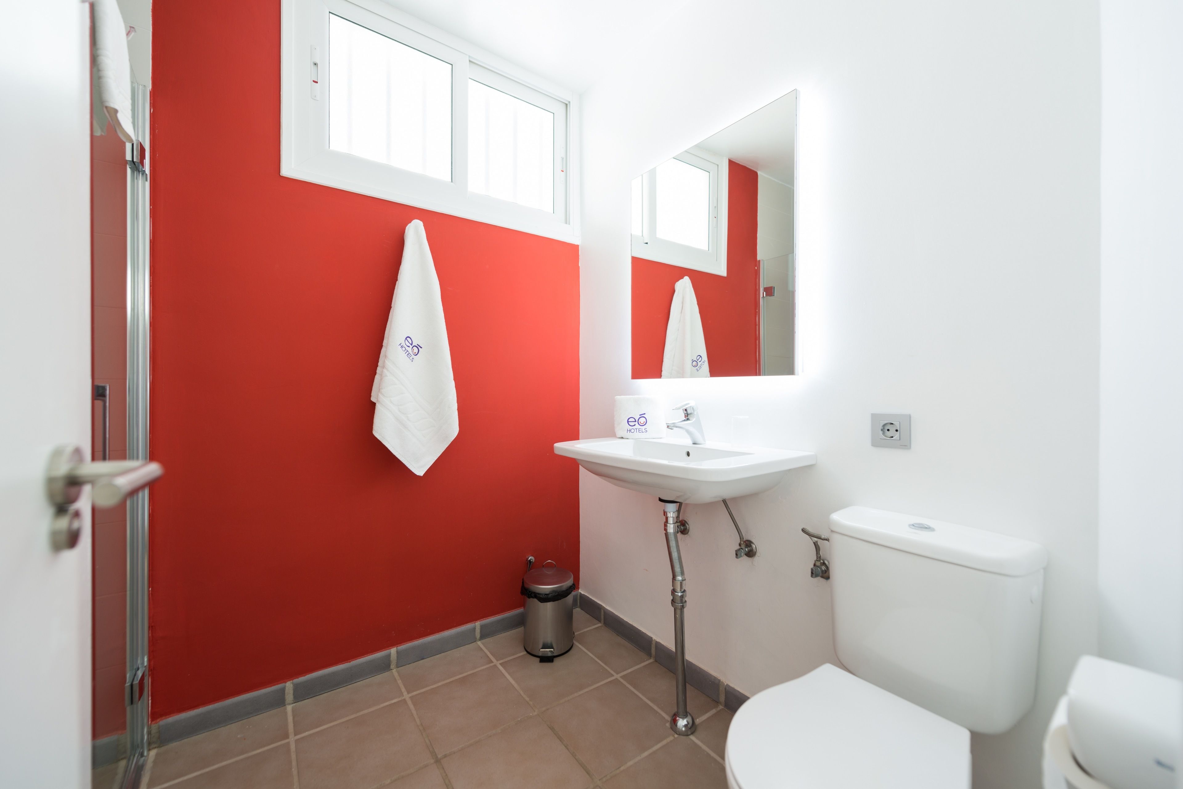 A bathroom with red walls, a white sink, and a toilet.