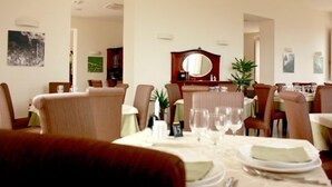 Un comedor con mesas dispuestas para el servicio, sillas y un espejo sobre la mesa.