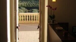 Una puerta abierta que da a un balcón con vistas a un paisaje montañoso.