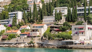 A coastal town with buildings along the waterfront, a stone wall, and a bridge.