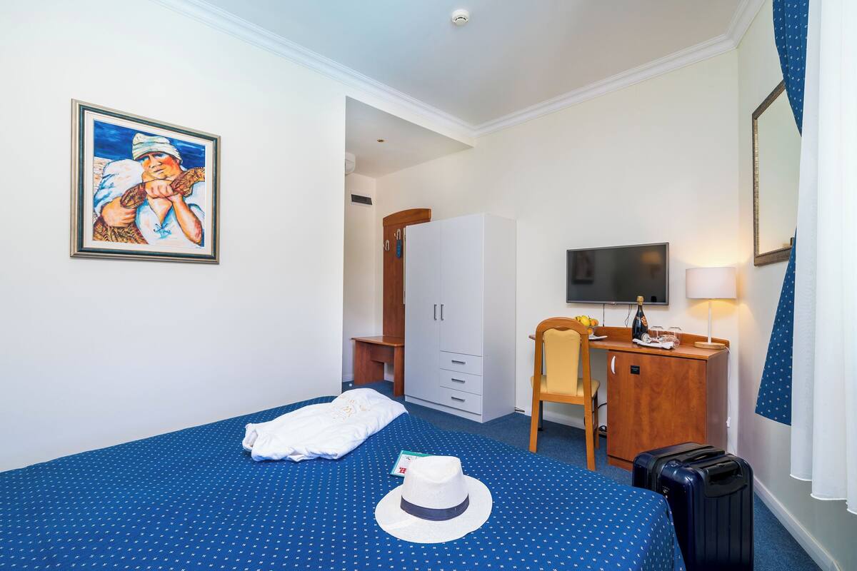 A hotel room with a bed, a desk, a television, and a wardrobe.