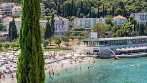 A coastal area with a beach, a water slide, and a building with a glass facade.